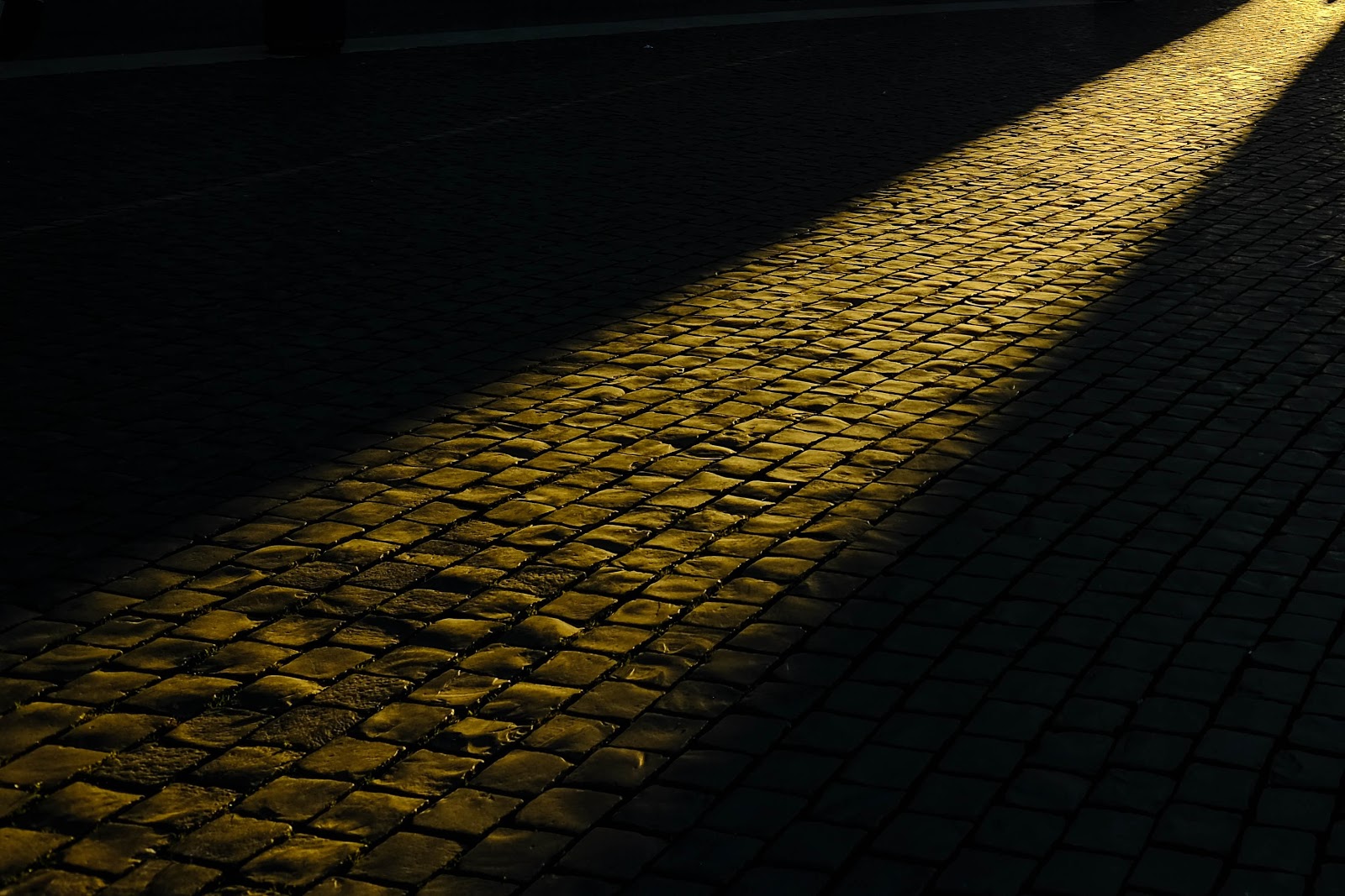 light shining in the dark on a cobblestone road